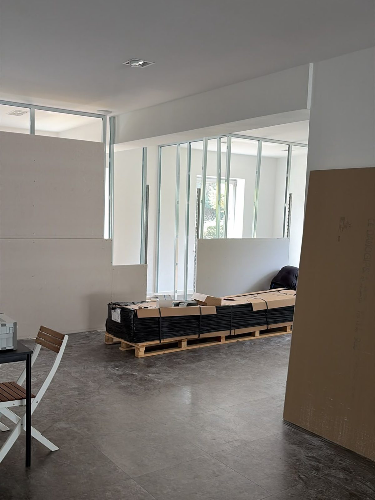 Blick durch die neue Innenverglasung, auf Paletten liegt Material für den weiteren Ausbau